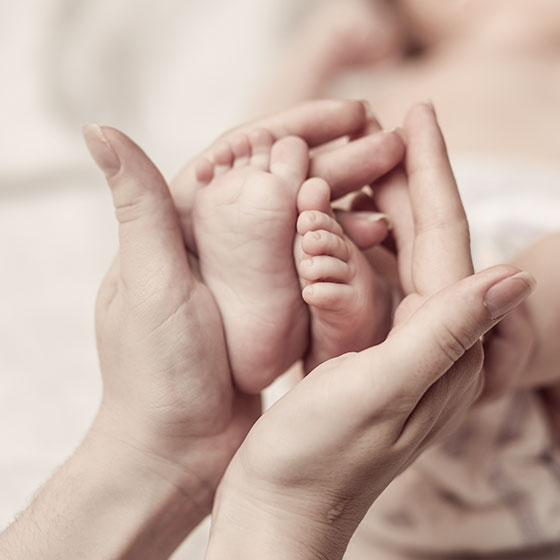 Photo de mains palpant les pieds d'un nouveau né